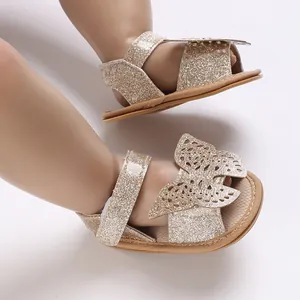 Close-up of baby girl golden glitter sandals with butterfly detail and soft sole.