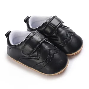 Close-up of black faux leather baby walker shoes with brogue detailing and rubber sole