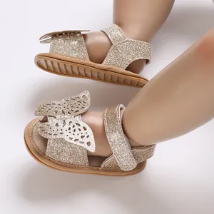 Detailed view of sparkly gold baby sandals with butterfly decor and soft soles.