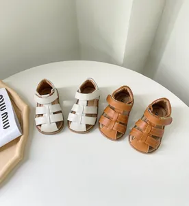 Vue détaillée des sandales romaines pour bébés en blanc et marron avec semelles souples.