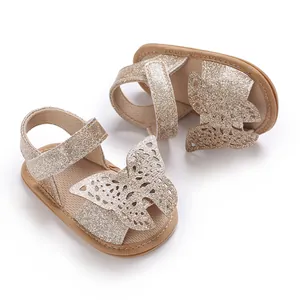 Close-up of sparkly gold baby girl sandals with elegant cutout butterfly wing detail