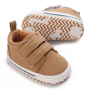 Detail of brown canvas baby sneakers with double Velcro straps and patterned rubber sole.
