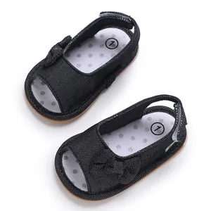 Nahaufnahme von schwarzen atmungsaktiven Baby-Sandalen mit Schleife und weicher Sohle.