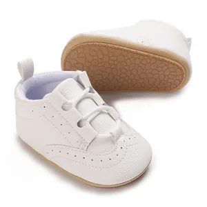 Close-up of white leather baby walking shoes with brogue details and non-slip soft soles