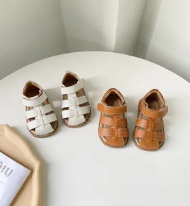 Vue détaillée de sandales romaines pour bébé en cuir blanc et marron sur une table blanche