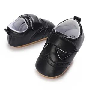 Detail view of black faux leather baby boy brogue pre-walker shoes with anti-slip rubber soles.