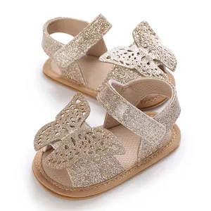 Detailed view of gold glitter baby sandals with butterfly cutout design for infant walkers.