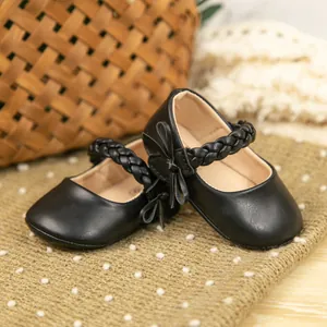 Nahaufnahme schwarzer PU-Leder Baby-Prinzessinenschuhe mit Schleife und Flechtriemen