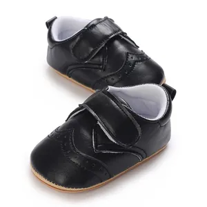 Macro detail of black leather baby walking shoes featuring non-slip brown rubber sole.