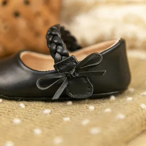 Nahaufnahme von schwarzen Baby-Prinzessin-Schuhen aus PU-Leder mit geflochtenem Riemen