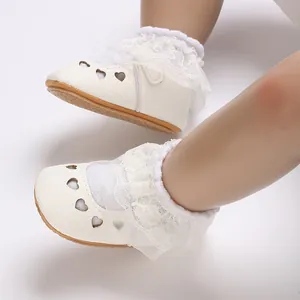 Close-up of white baby princess shoes with heart cutouts and delicate lace trim