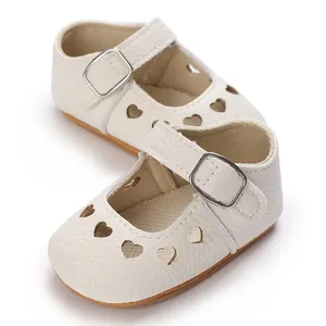 Close-up view of white infant Mary Jane shoes featuring heart-shaped cutout designs