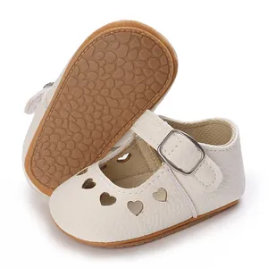 Close-up detail of white baby princess shoes featuring heart cutouts and brown rubber sole