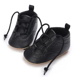 Macro view of black faux-leather baby sneakers with soft sole and lace-up detail