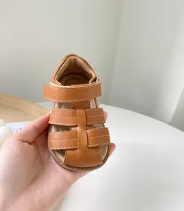 Gros plan de sandales de marche pour bébé en cuir marron avec surpiqûres blanches