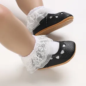 Close-up of baby girl princess shoes with heart cutouts and white lace socks detail