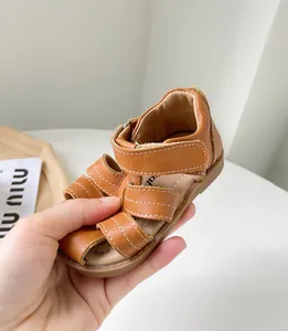 Gros plan sandale bébé en cuir marron avec semelle souple et brides scratch