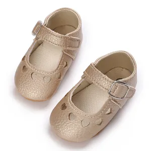 Macro view of golden baby Mary Janes featuring decorative heart cutouts and buckles.