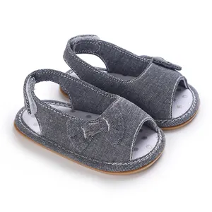 Detailansicht graue Baby-Sandalen mit Schleife, atmungsaktives Mesh und gepunkteter Sohle.