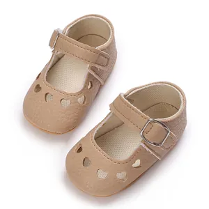 Gros plan de chaussures Mary Jane pour bébé beiges avec découpes en cœur et boucle.