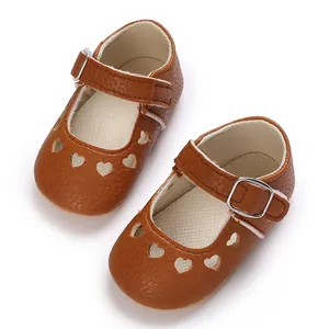 Detail of brown baby shoes with cute heart cutouts and metallic buckle strap.