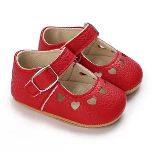 Close-up detail shot of red baby princess shoes with heart cutouts and silver buckle