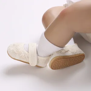 Primer plano de zapatos de encaje crema para bebé con correa de velcro y suela