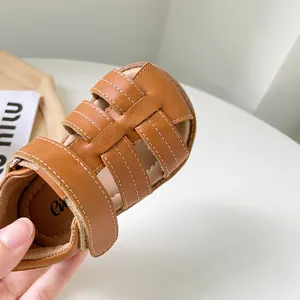 Gros plan de sandales romaines en cuir marron pour bébés filles avec semelles souples