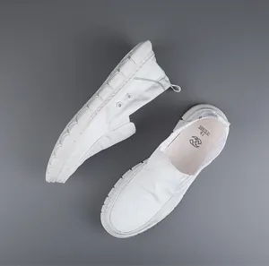 Detailed top-down view of white breathable slip-on canvas loafers for men on gray backdrop