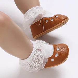 Close-up of brown baby princess shoes with heart cutouts and white lace socks