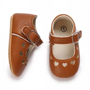 Close-up of brown baby Mary Jane shoes with heart-shaped cutouts and buckle strap