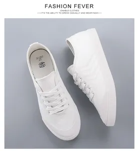 Vista dettagliata dall'alto di sneakers in tela bianche minimaliste da donna su sfondo grigio