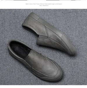 Detailed top-down view of grey leather slip-on loafers on a textured grey surface