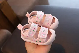 Gros plan de sandales roses pour bébé avec motifs fraises et lapins et semelles souples