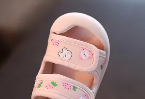 Détail des motifs mignons de fraise et d'ours sur les sandales roses pour bébés filles