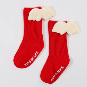 Close-up of red ribbed baby socks featuring cute plush angel wings and non-slip soles.