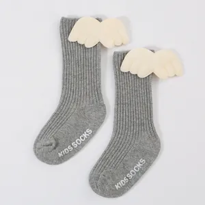 Close-up of grey ribbed baby socks with plush angel wings and non-slip soles.