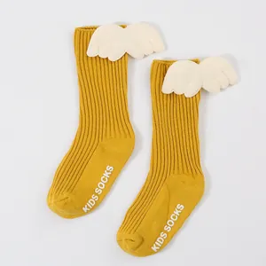 Close-up of yellow ribbed baby socks featuring cute 3D plush white wing decorations