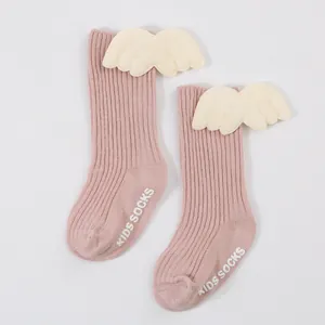 Close-up of pink ribbed baby socks with cute plush wings and anti-slip sole grips