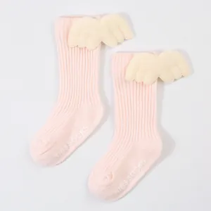 Close-up detail of pink ribbed baby socks featuring plush angel wings and non-slip grips.