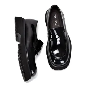Close-up van zwarte glanzend leren loafers met dikke zool en penny design detail.