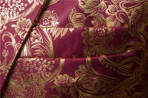 Dettaglio macro di giacca da uomo bordeaux con motivo floreale paisley in oro lucido