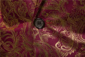 Dettaglio macro di blazer da uomo con motivo floreale dorato e bottone decorato.