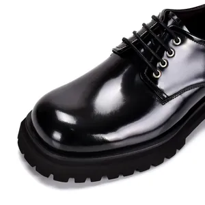 Detailed view of a black glossy leather Derby shoe featuring a thick lug sole and round toe