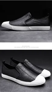 Detail view of men's black leather slip-on shoes with distinctive white rubber toe caps.
