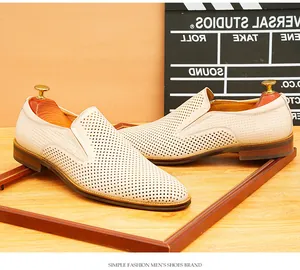 Vue détaillée des mocassins en cuir perforé blanc sur un support en bois rustique