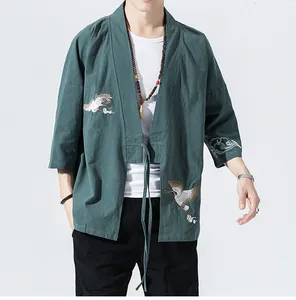 Detailed view of green kimono cardigan with white crane embroidery in traditional style.