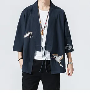 Detail of navy blue kimono cardigan featuring intricate white crane embroidery.