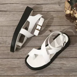 Elegante witte teensandalen met dikke zwarte platformzolen op rustiek houten vloer