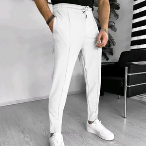 Detailed view of men's white waffle knit drawstring trousers in a modern indoor setting